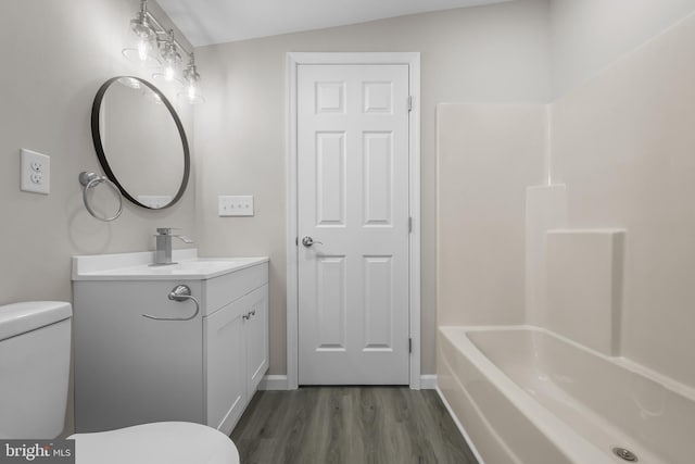 full bathroom with vanity, vaulted ceiling, wood-type flooring, washtub / shower combination, and toilet