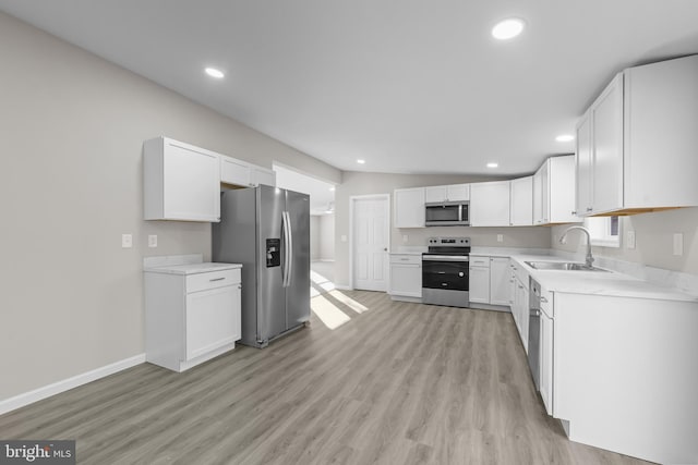 kitchen featuring sink, light hardwood / wood-style floors, lofted ceiling, white cabinets, and appliances with stainless steel finishes