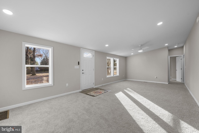 foyer entrance with light colored carpet, ceiling fan, and a healthy amount of sunlight