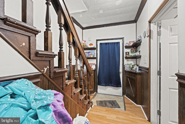 entrance foyer featuring light hardwood / wood-style floors, a textured ceiling, and ornamental molding