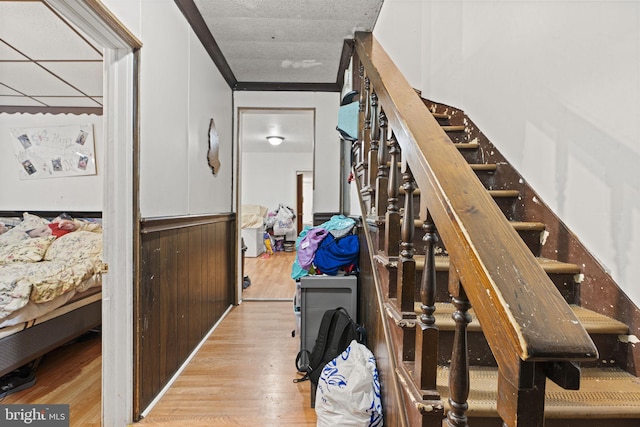 stairs with crown molding, wood-type flooring, and a textured ceiling