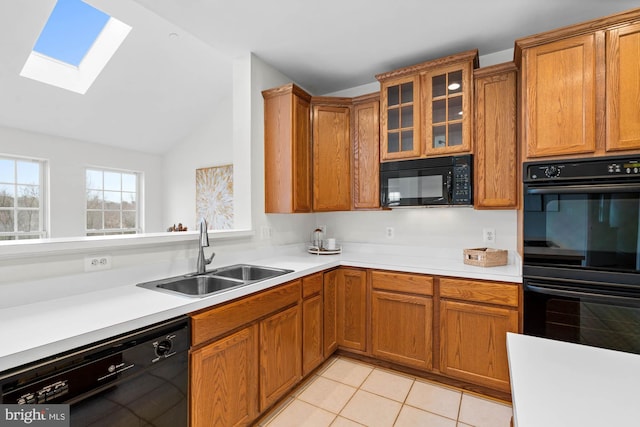 kitchen featuring sink, black appliances, vaulted ceiling with skylight, and light tile patterned flooring