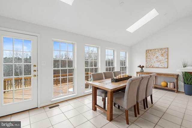 tiled dining area featuring plenty of natural light and lofted ceiling with skylight