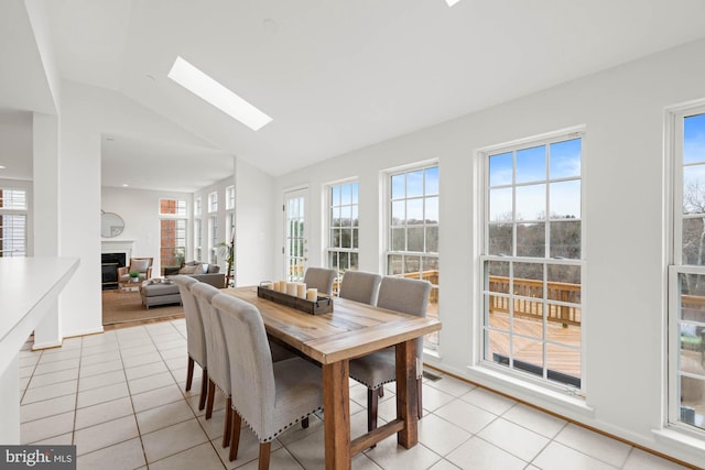 dining area featuring lofted ceiling with skylight, plenty of natural light, and light tile patterned floors