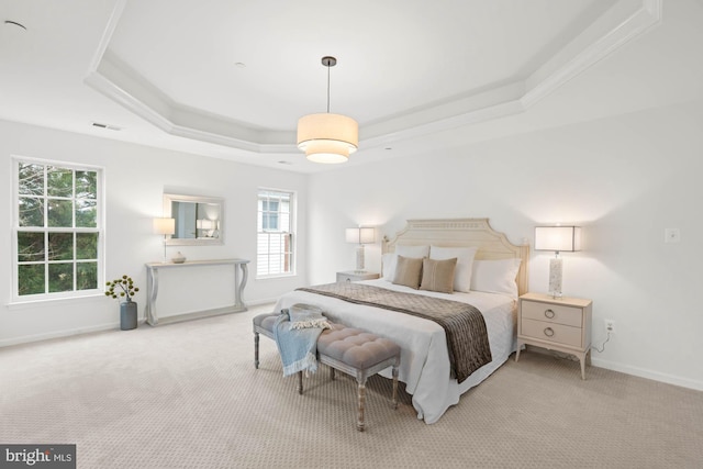 bedroom featuring a tray ceiling, light carpet, and ornamental molding