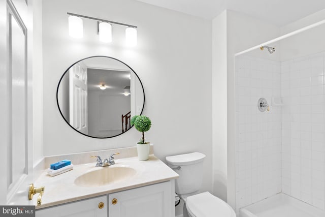 bathroom featuring vanity, a tile shower, and toilet