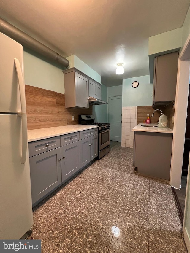 kitchen with gray cabinets, white fridge, sink, and stainless steel range with gas stovetop