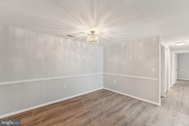 empty room featuring hardwood / wood-style flooring and a notable chandelier