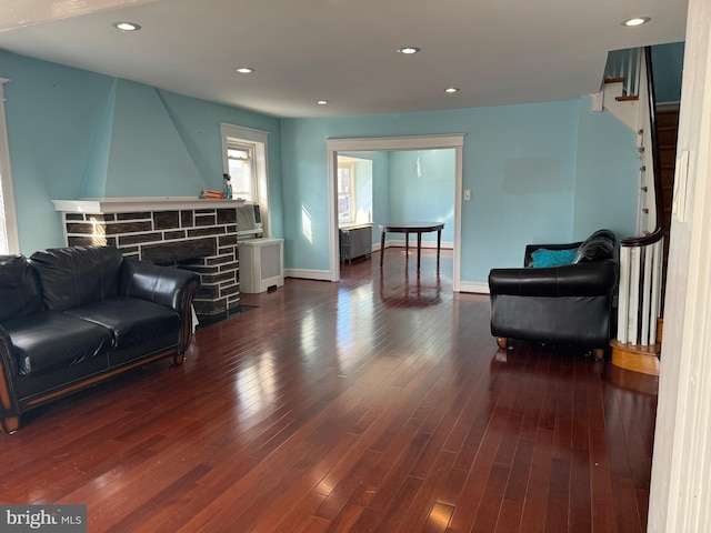 living area featuring dark hardwood / wood-style flooring and a stone fireplace