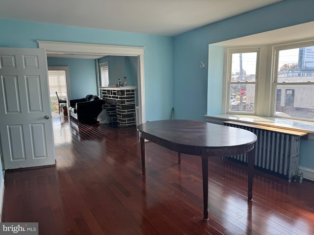 dining room featuring a fireplace, radiator heating unit, and dark hardwood / wood-style floors