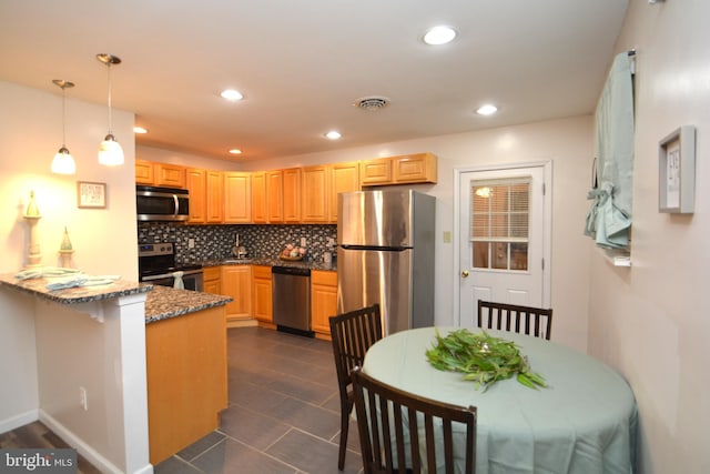 kitchen with hanging light fixtures, stainless steel appliances, kitchen peninsula, dark stone countertops, and decorative backsplash