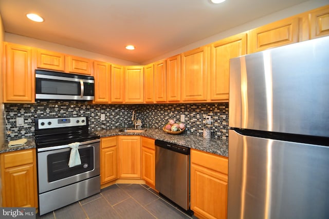 kitchen featuring appliances with stainless steel finishes, backsplash, dark tile patterned flooring, and sink