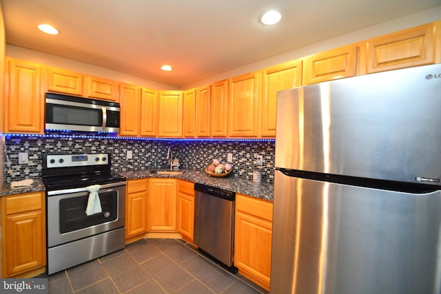 kitchen with decorative backsplash, sink, stainless steel appliances, and dark tile patterned flooring