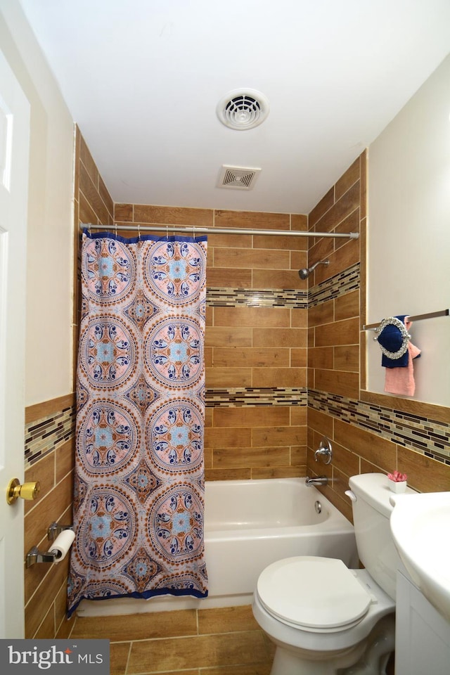 full bathroom with tile walls, wood-type flooring, toilet, vanity, and shower / tub combo