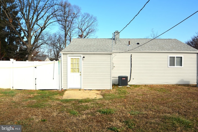 rear view of property featuring cooling unit and a lawn