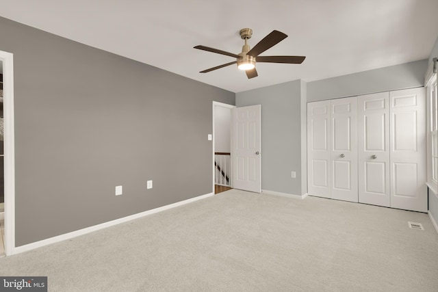 unfurnished bedroom with ceiling fan, light colored carpet, and a closet