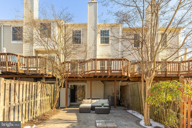 rear view of property featuring a wooden deck, an outdoor hangout area, and a patio