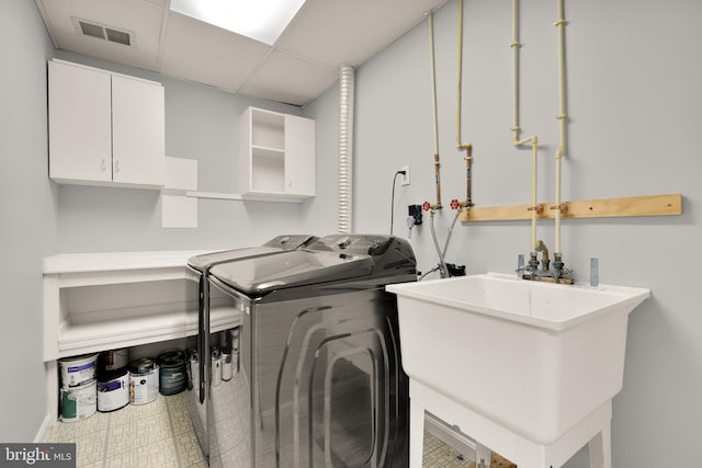 washroom with sink, cabinets, and washing machine and dryer