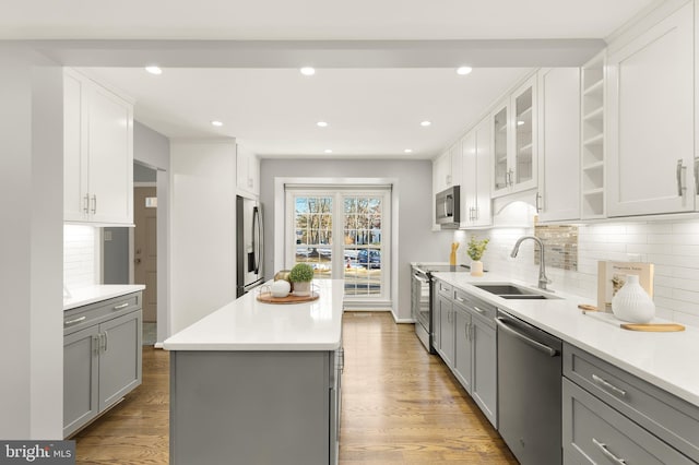 kitchen with appliances with stainless steel finishes, decorative backsplash, sink, a kitchen island, and gray cabinets