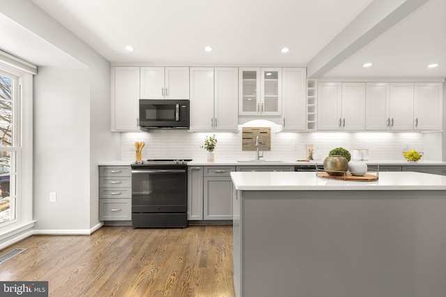 kitchen featuring decorative backsplash, sink, range with electric stovetop, hardwood / wood-style flooring, and gray cabinetry