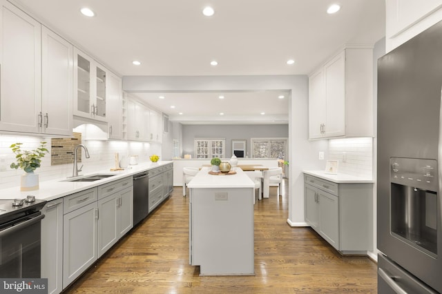 kitchen with sink, stainless steel appliances, a kitchen island, and white cabinetry