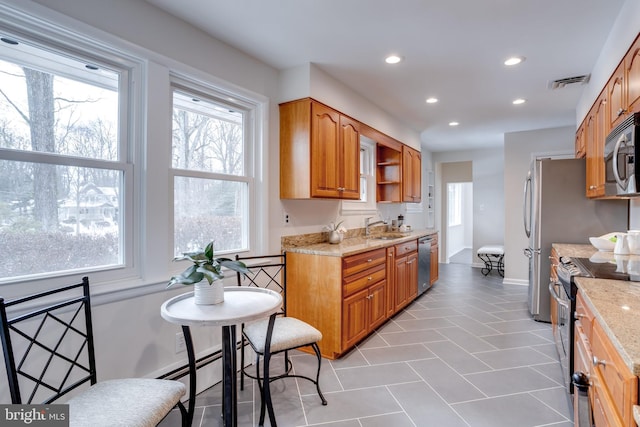 kitchen with light stone counters, stainless steel appliances, light tile patterned floors, and sink