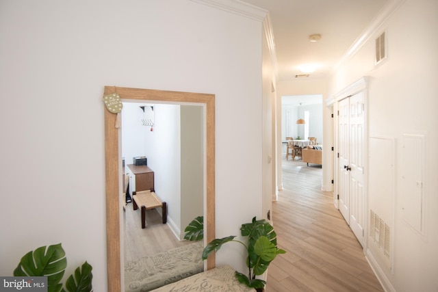 corridor with light hardwood / wood-style flooring and crown molding