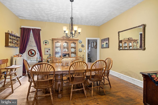 dining space with hardwood / wood-style flooring, a textured ceiling, and a chandelier