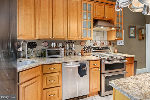 kitchen with sink, light tile patterned floors, light stone countertops, stainless steel appliances, and extractor fan