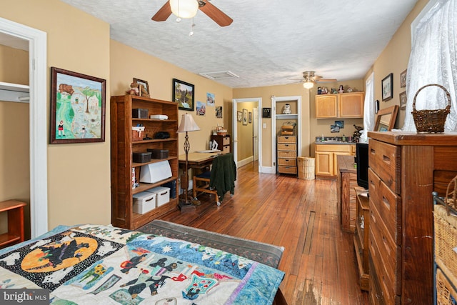 bedroom featuring ceiling fan, dark hardwood / wood-style flooring, and a textured ceiling