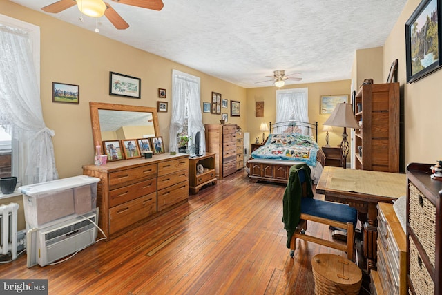 bedroom featuring radiator, ceiling fan, dark hardwood / wood-style flooring, and a textured ceiling