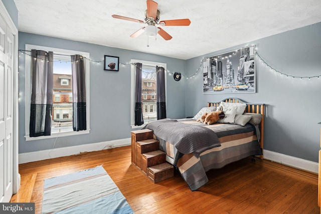 bedroom featuring ceiling fan, wood-type flooring, and a textured ceiling