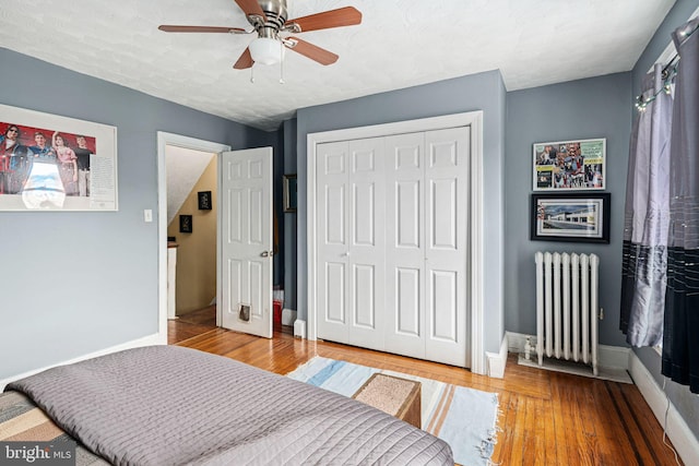 bedroom featuring ceiling fan, radiator heating unit, a textured ceiling, a closet, and hardwood / wood-style flooring