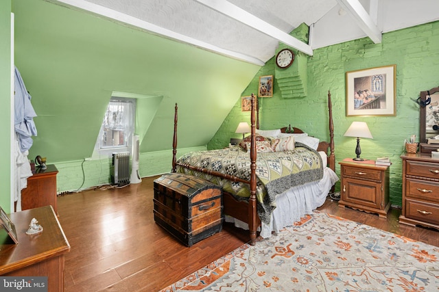 bedroom with lofted ceiling with beams, dark hardwood / wood-style floors, brick wall, and radiator