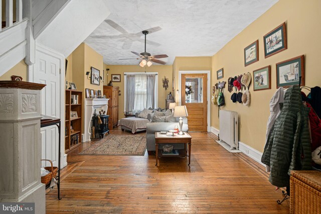 living room with radiator heating unit, a textured ceiling, hardwood / wood-style flooring, and ceiling fan