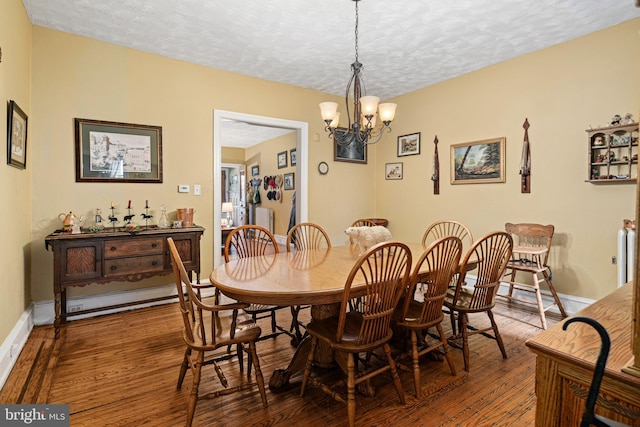 dining space with a notable chandelier, wood-type flooring, a textured ceiling, and a baseboard radiator