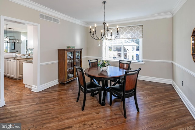 dining space with dark hardwood / wood-style flooring, ornamental molding, and an inviting chandelier