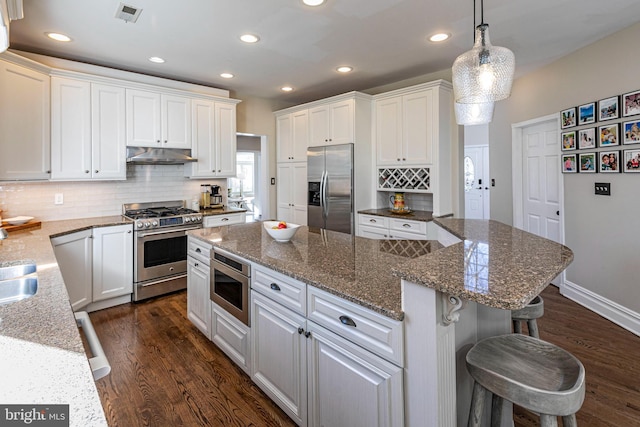 kitchen featuring white cabinetry, a center island, stainless steel appliances, pendant lighting, and a kitchen bar