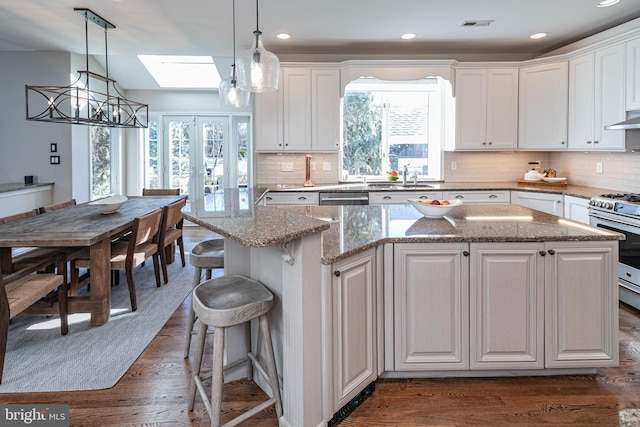 kitchen with a center island, a skylight, white cabinetry, and stainless steel appliances