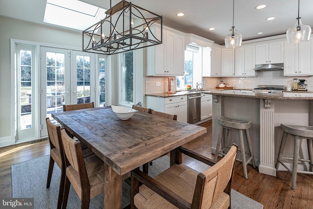 kitchen featuring dishwasher, white cabinetry, hanging light fixtures, and a skylight