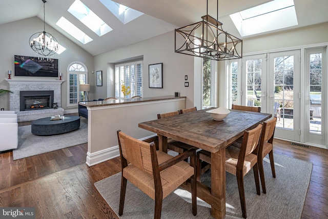 dining space with dark hardwood / wood-style flooring, lofted ceiling with skylight, and a fireplace