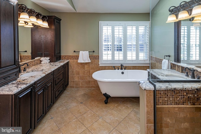 bathroom featuring tile patterned floors, a tub, vanity, and tile walls