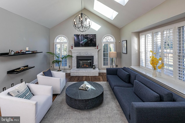 living room featuring hardwood / wood-style flooring, lofted ceiling, a brick fireplace, and a chandelier