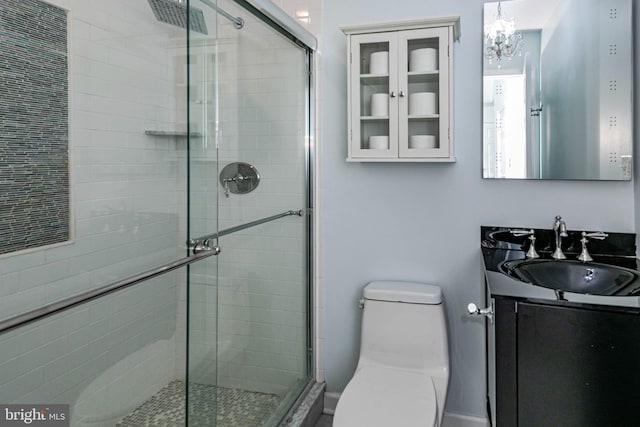 bathroom with vanity, toilet, and a shower with door