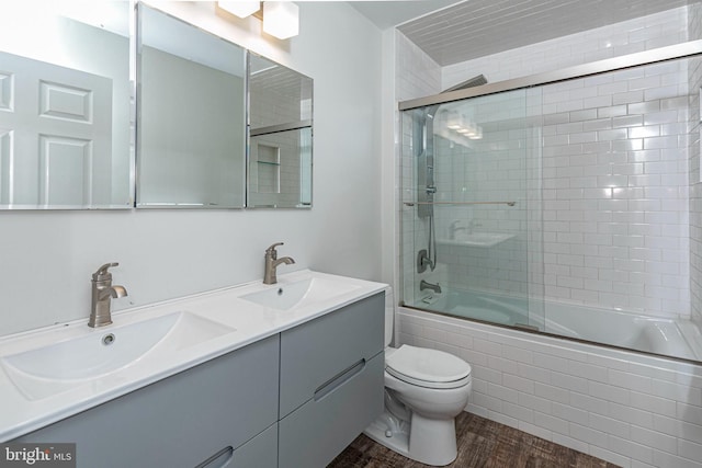 full bathroom featuring wood-type flooring, vanity, toilet, and bath / shower combo with glass door