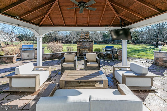 view of patio with a gazebo, area for grilling, an outdoor living space with a fireplace, and ceiling fan