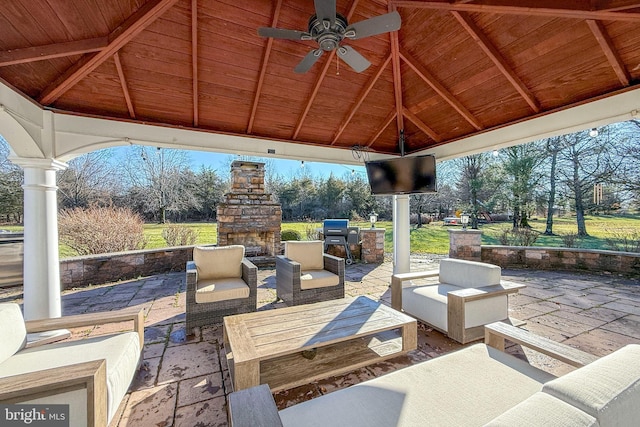 view of patio with a gazebo, ceiling fan, exterior kitchen, and an outdoor living space with a fireplace