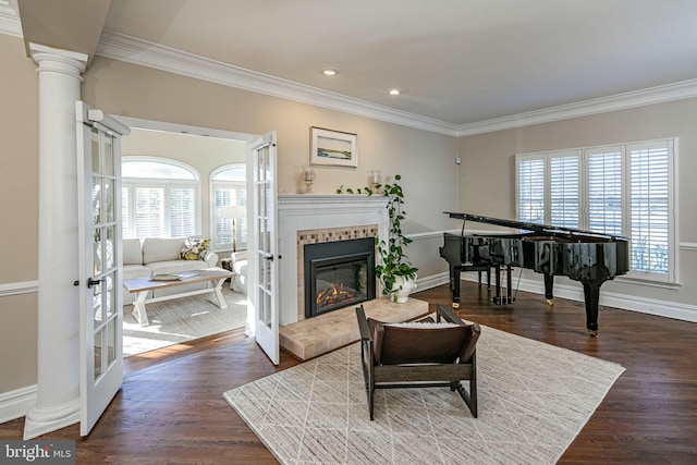 living area featuring french doors, dark hardwood / wood-style floors, crown molding, and a tiled fireplace