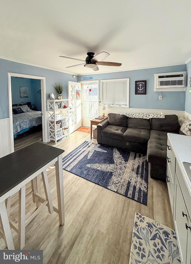 living room with light hardwood / wood-style flooring, a wall mounted AC, and ceiling fan