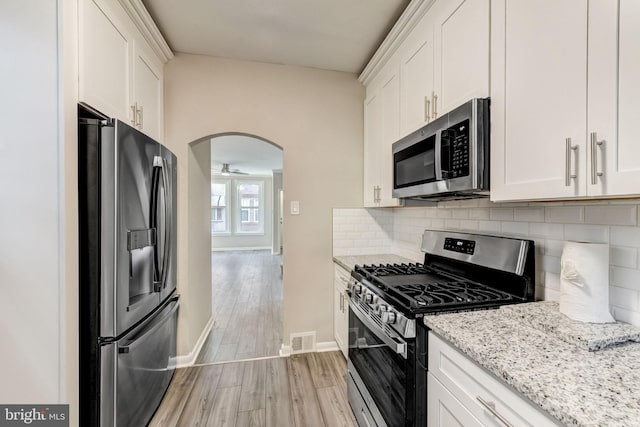 kitchen with backsplash, light stone counters, white cabinets, and appliances with stainless steel finishes